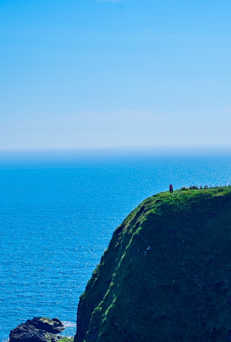 Green sea cliff above blue water